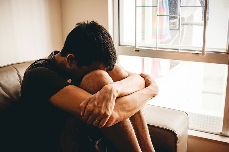 sad boy sitting next to a window