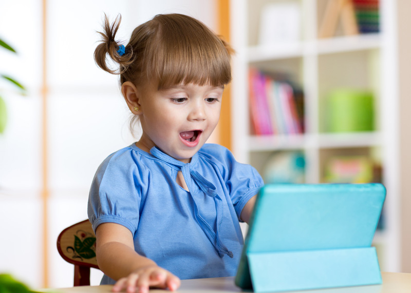 child girl playing with a digital tablet at home