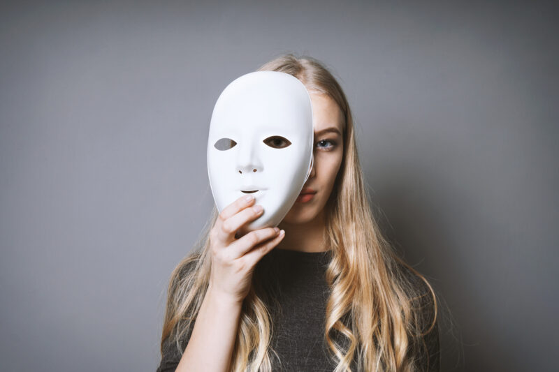 teen girl hiding face behind mask