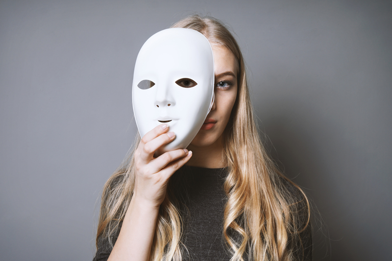 teen girl hiding face behind mask