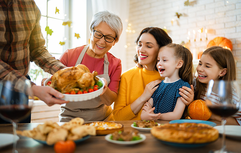 Happy family enjoying Thanksgiving holiday dinner with grandparents, parents and children.