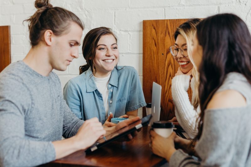 A group of friends at a coffee shop using technology