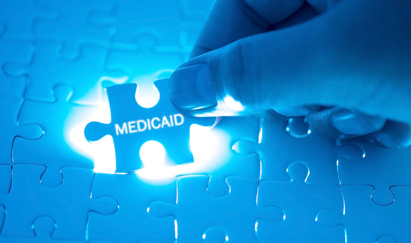 Doctor holding a jigsaw puzzle with MEDICAID word