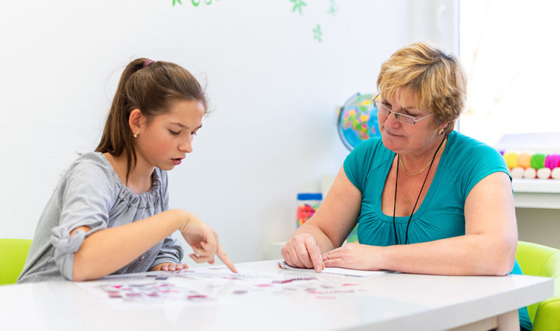 Mature female therapist working with a teenage girl with learning difficulties to master logical tests.