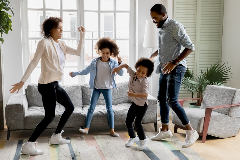 African American family dancing in living room