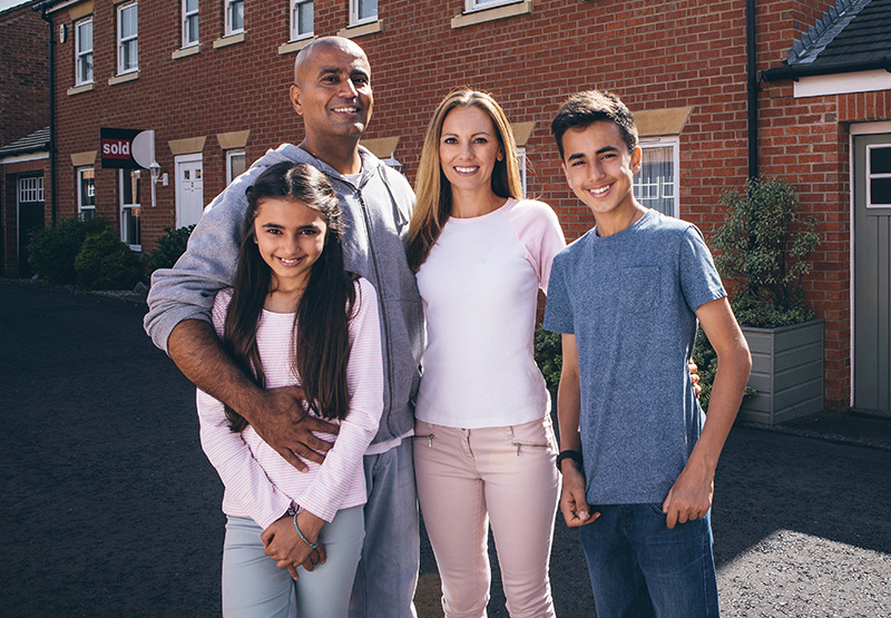 Happy family posing together outside of their home.