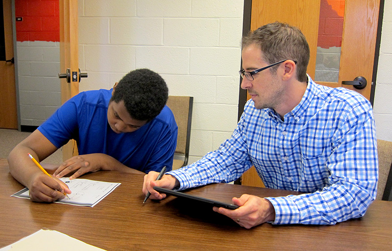 Dr. Bradley Stevenson admires the drawing skills of student Tyler.
