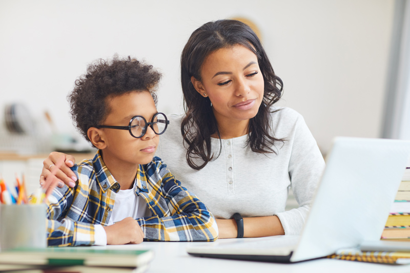 Mother with son at laptop for remote learning