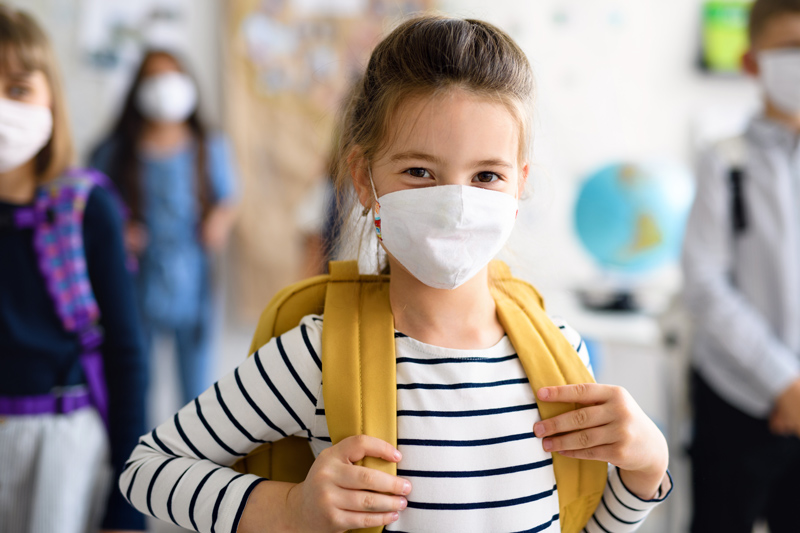 Young girl wearing a mask at school