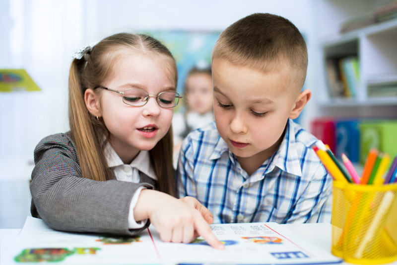 A young female student helping her peer at school