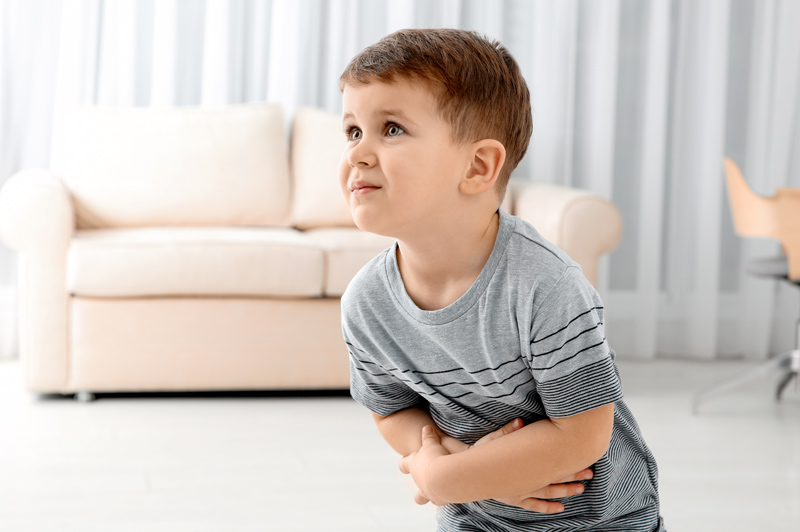 Little boy suffering from nausea with an upset stomach in living room