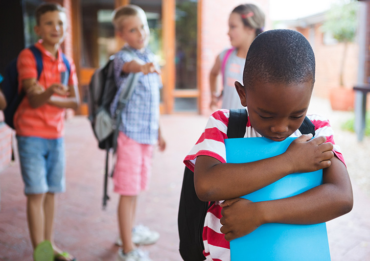 A young African American boy being bullied at school by his peers