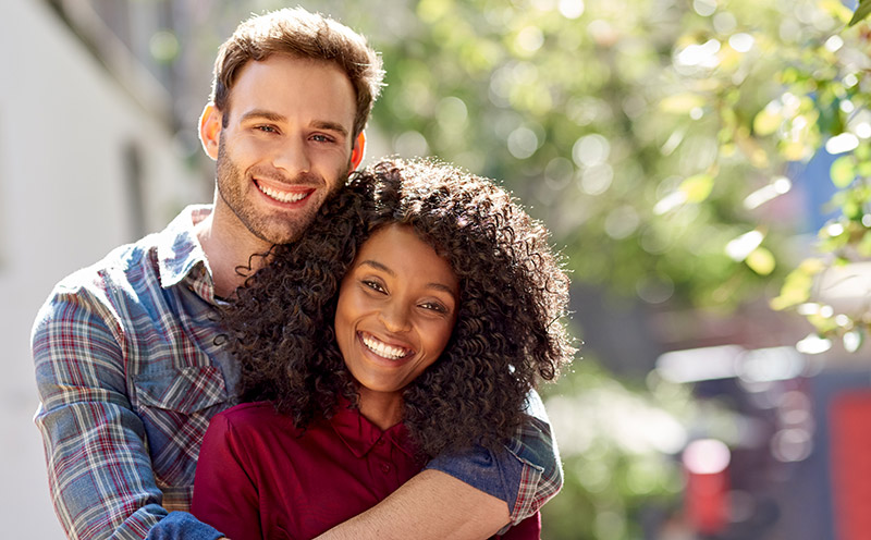 Neurodiverse couple affectionately standing together outside on a sunny day