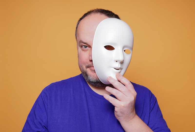 man taking off mask revealing face and identity