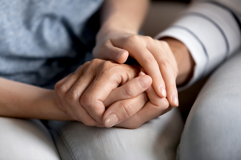 Person holding hand to support a grieving friend